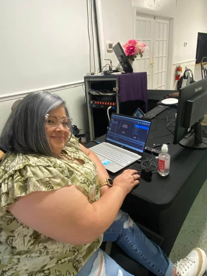 Woman at desk with laptop displaying audio production software in home studio setup