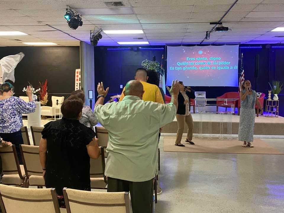 Congregation worshipping together in modern church sanctuary with stage and blue lighting