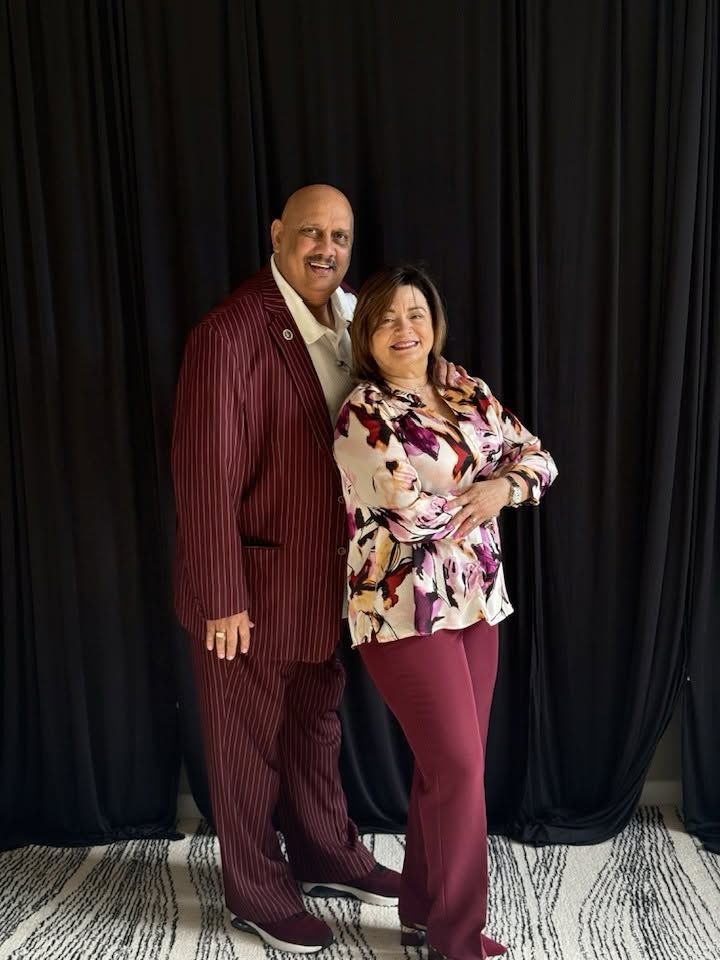 Two professionals posing together against black curtains in business attire