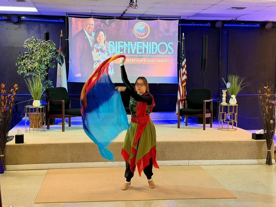 Woman performing with red and blue fabric at formal event stage with welcome banner